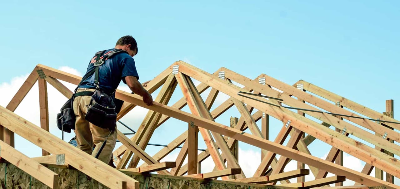 Construction man working on roof structure of building.