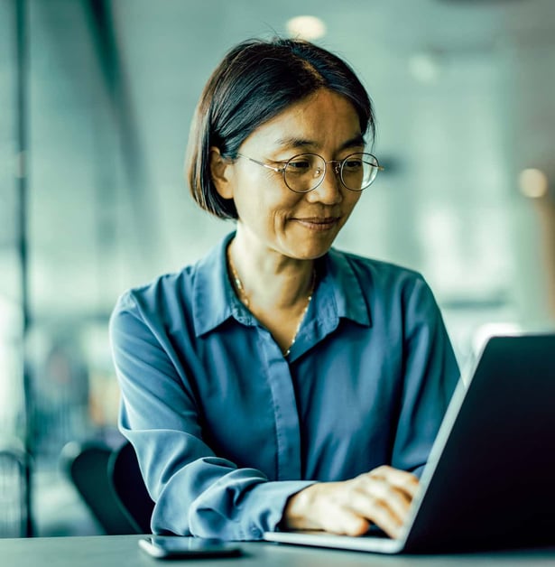A woman works on a laptop in an open office.